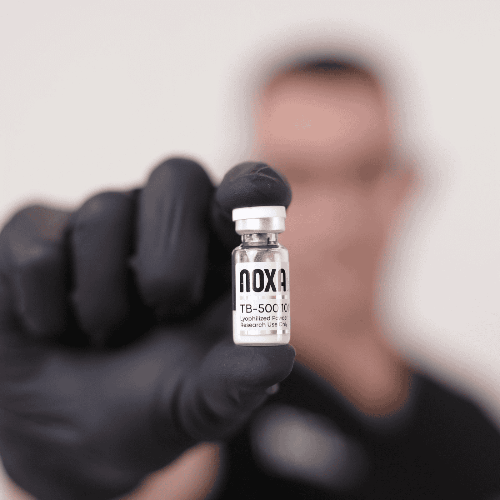 TB-500 Close-up of Noxa Labs vaccine vial held by gloved hand.